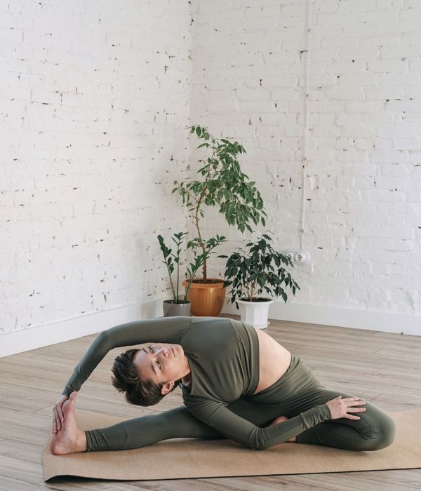 Woman in a calm yoga pose in a green-tinted studio.